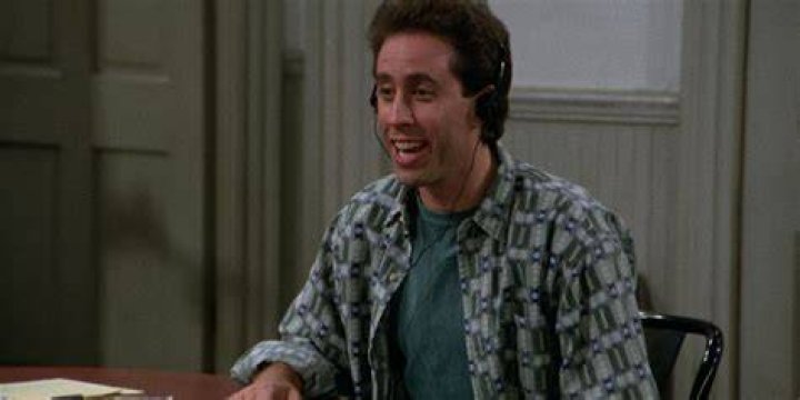 Jerry Seinfeld wearing headphones and sitting down in Seinfeld's 